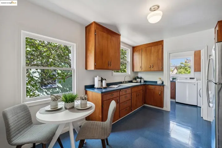 Kitchen with dark countertops, brown cabinets, freestanding refrigerator, and dark flooring