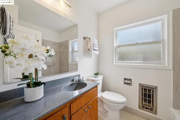 Bathroom featuring vanity, heating unit, and light tile patterned floors