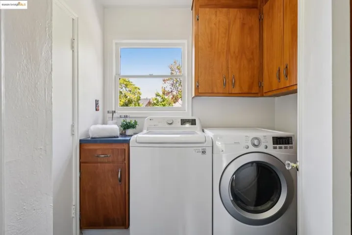 Washroom featuring cabinet space, separate washer and dryer, and a textured wall