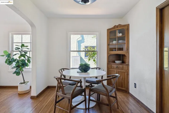 Dining space featuring a textured wall, arched walkways, and dark wood-style flooring