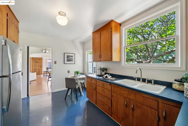 Kitchen featuring dark countertops, freestanding refrigerator, brown cabinets, and dark floors