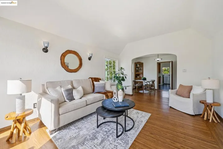 Living area featuring arched walkways, lofted ceiling, and dark wood-type flooring