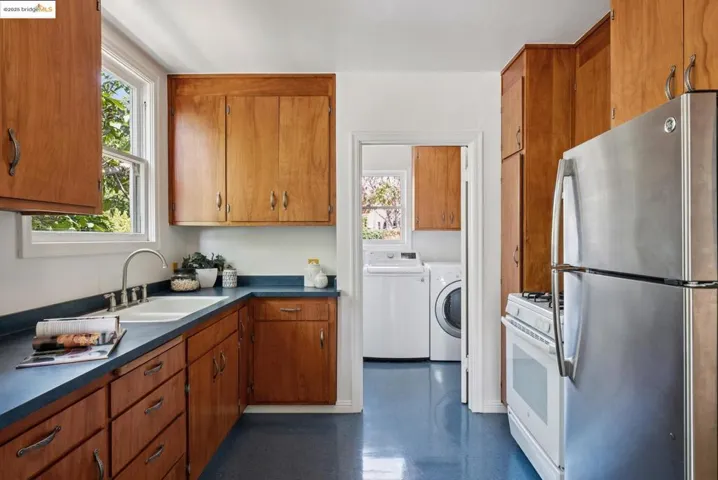 Kitchen featuring dark countertops, freestanding refrigerator, brown cabinetry, and white range with gas stovetop