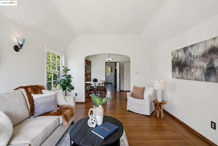 Living room featuring arched walkways, vaulted ceiling, and wood finished floors