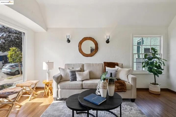 Living area with wood finished floors, a textured wall, and lofted ceiling