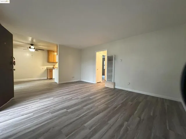 Unfurnished living room featuring dark wood-type flooring, a heating unit, and a ceiling fan