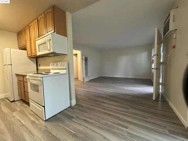 Kitchen featuring white appliances, light countertops, light wood-style floors, and brown cabinetry