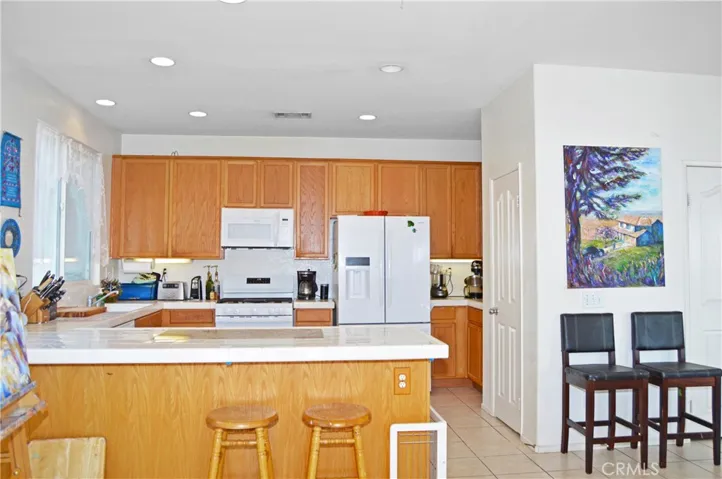 Light and Bright Kitchen with An Added Breakfast Bar with a Granite Insert for Dough-Making, Tile Floors, & a Pantry