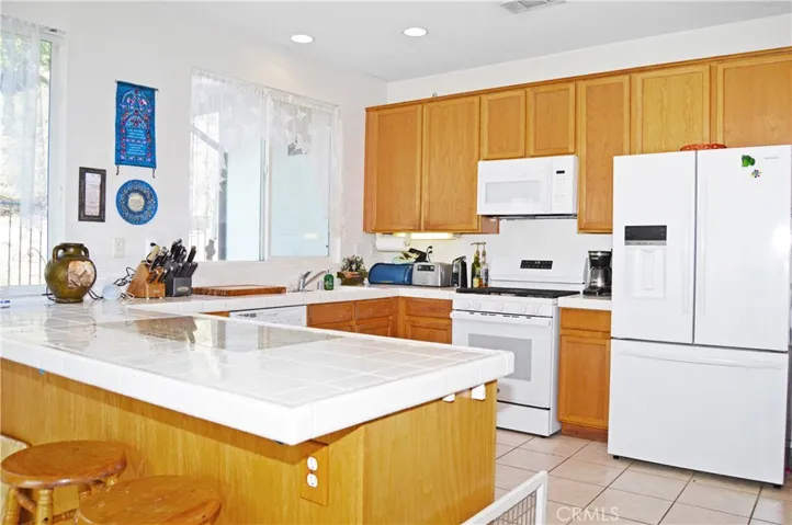 Light and Bright Kitchen with An Added Breakfast Bar with a Granite Insert for Dough-Making, Tile Floors, & a Pantry