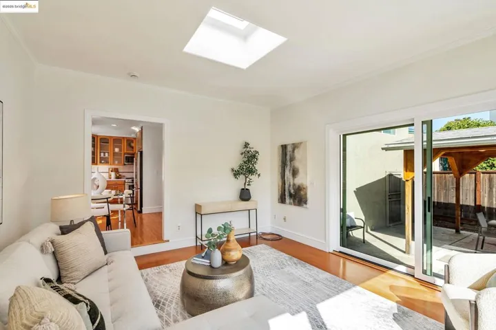 Living area with a skylight, wood finished floors, and ornamental molding