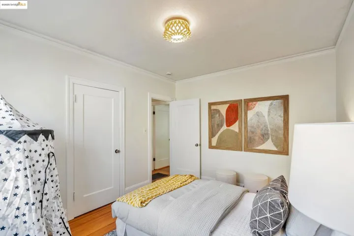 Bedroom with wood finished floors and crown molding