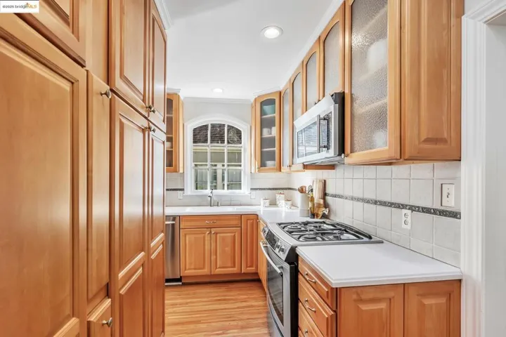 Kitchen with stainless steel appliances, decorative backsplash, light wood-type flooring, light countertops, and recessed lighting