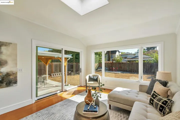 Sunroom / solarium with wood finished floors, a skylight, and vaulted ceiling