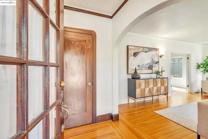 Foyer entrance featuring crown molding, arched walkways, and wood finished floors