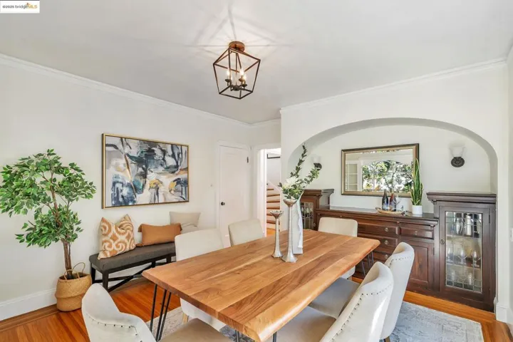 Dining area featuring light wood-type flooring, ornamental molding, stairway, and a chandelier