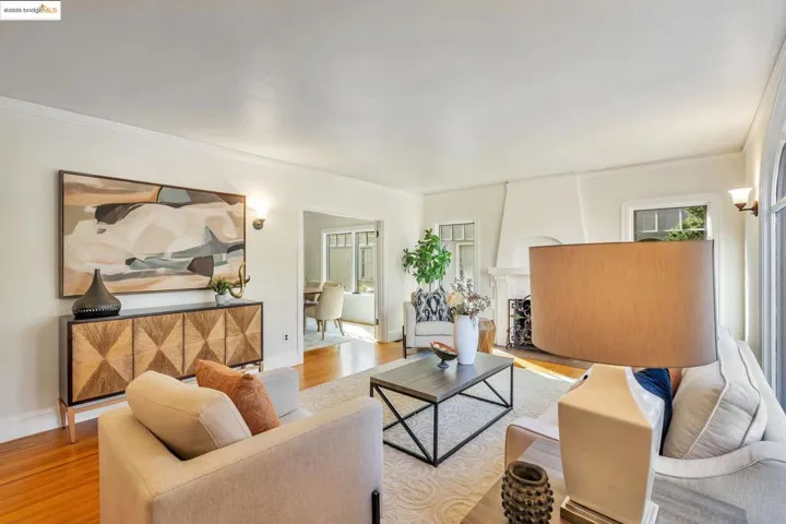 Living room with wood finished floors, a large fireplace, and crown molding