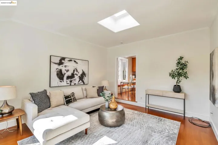 Living area featuring a skylight, wood finished floors, and ornamental molding
