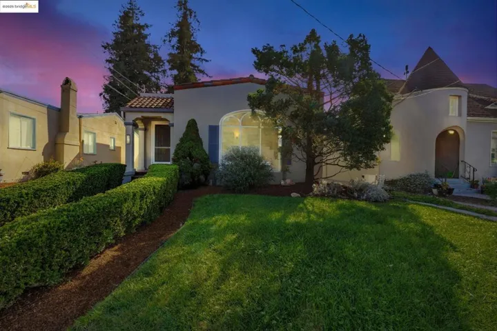 Mediterranean / spanish-style house with stucco siding, a front lawn, a tiled roof, and a chimney