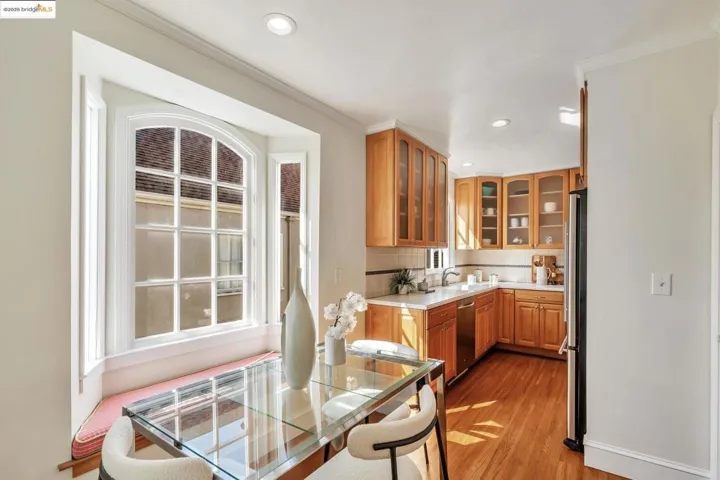 Kitchen with light countertops, glass insert cabinets, light wood-style flooring, backsplash, and recessed lighting