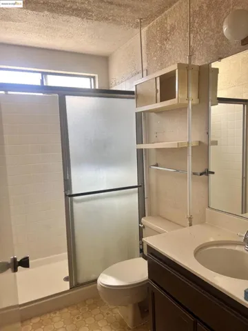 Full bath with vanity, a stall shower, and a textured ceiling