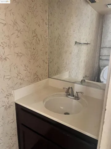Bathroom featuring wallpapered walls and vanity