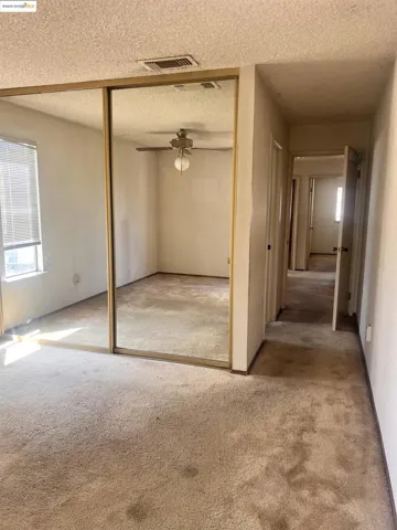 Unfurnished bedroom featuring a textured ceiling, carpet floors, a closet, and ceiling fan