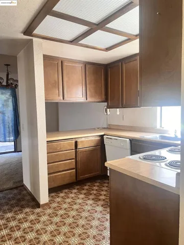 Kitchen with light countertops, dishwasher, a textured ceiling, a chandelier, and plenty of natural light