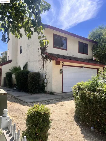 View of front of home featuring a garage, stucco siding, a tiled roof, and driveway