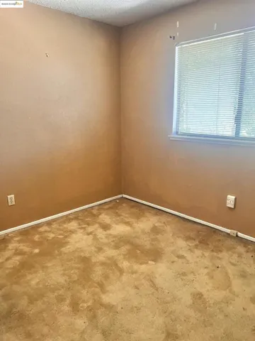 Carpeted empty room with baseboards and a textured ceiling