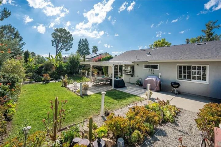 Large lush backyard with a patio cover, koi pond, succulent garden, wooden deck, and a jacuzzi