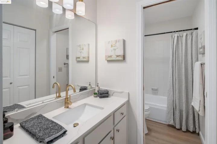 Full bathroom featuring shower / bath combo, vanity, light wood-style floors, and a closet