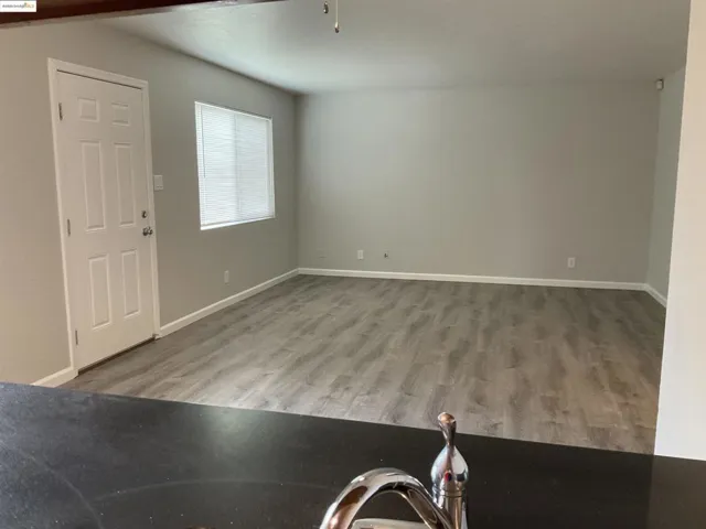 Unfurnished living room featuring light wood-style flooring and baseboards