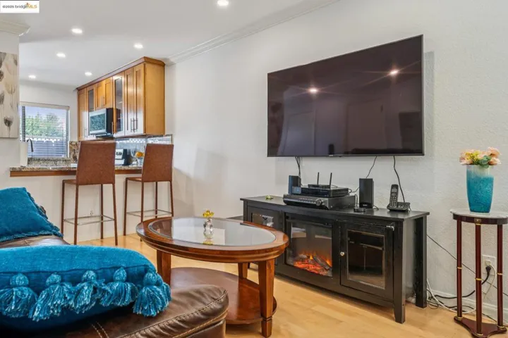 Living area with light wood finished floors, ornamental molding, and recessed lighting