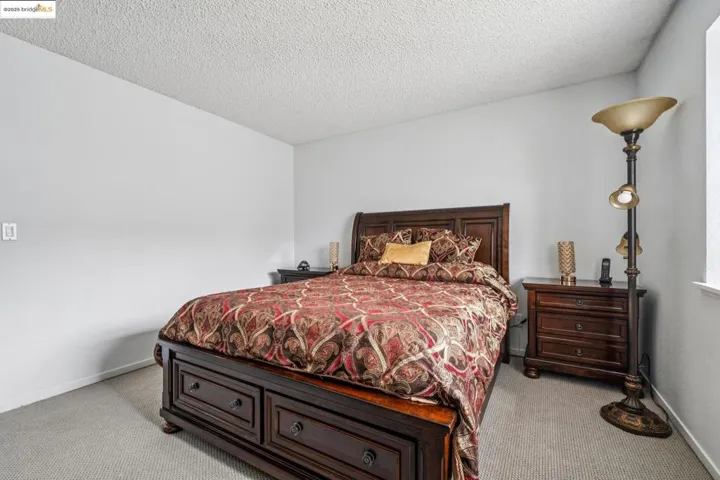 Carpeted bedroom featuring baseboards and a textured ceiling