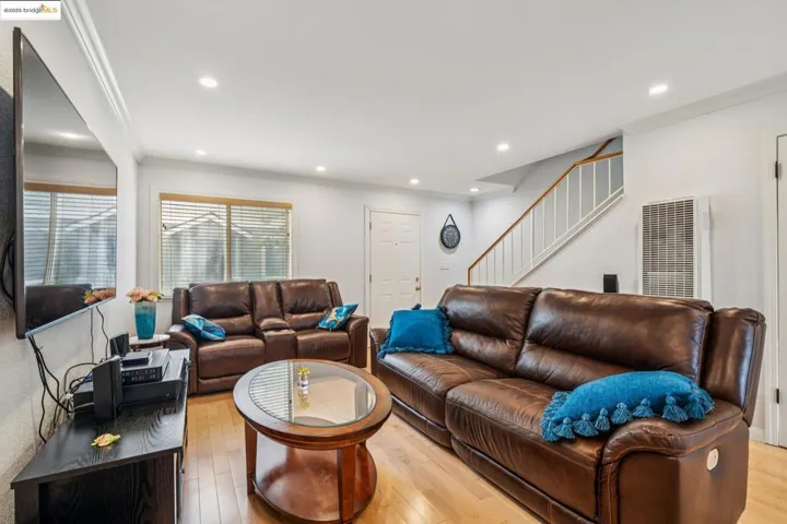 Living area featuring crown molding, light wood finished floors, recessed lighting, stairway, and a heating unit