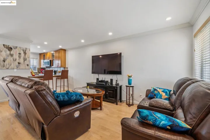 Living room with ornamental molding, recessed lighting, and light wood-style floors
