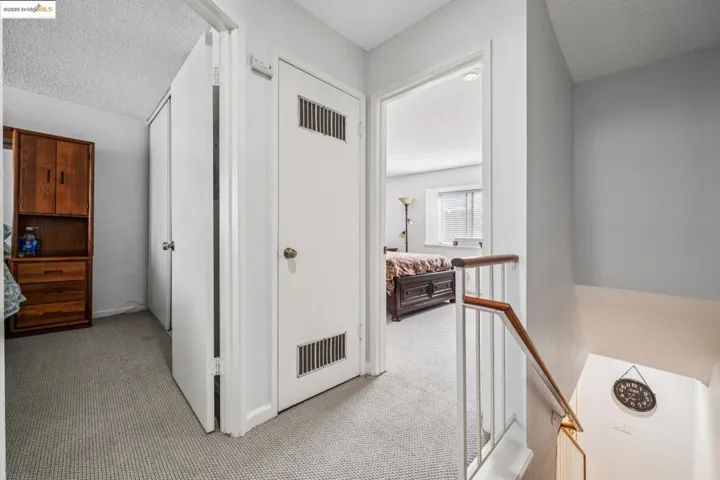Hall featuring a textured ceiling, light carpet, and an upstairs landing