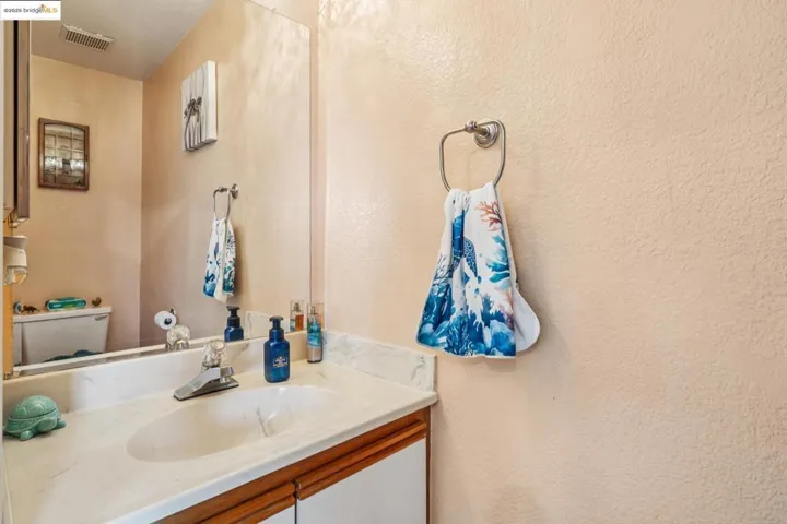 Half bath featuring a textured wall and vanity