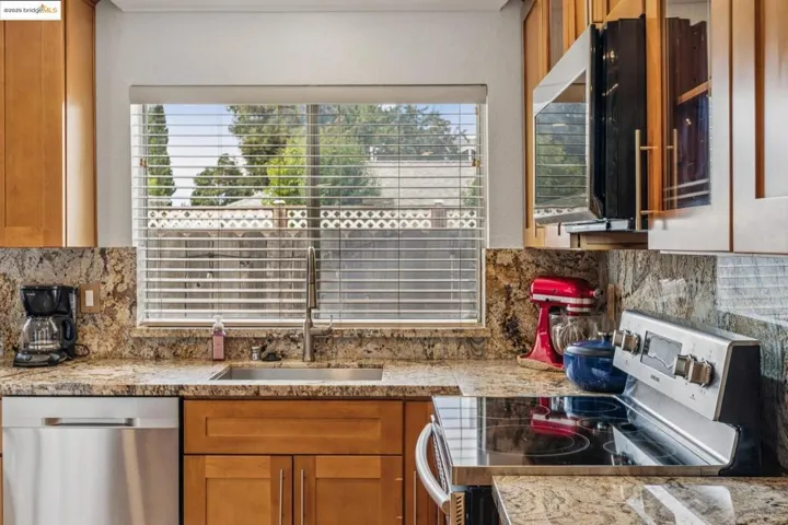 Kitchen with tasteful backsplash, stainless steel appliances, light stone counters, and brown cabinetry