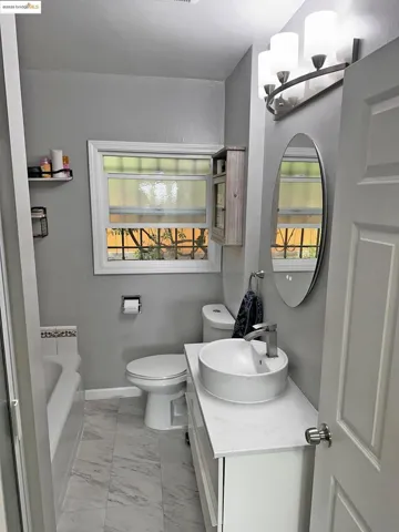 Full bathroom with light marble finish flooring, a garden tub, vanity, and plenty of natural light