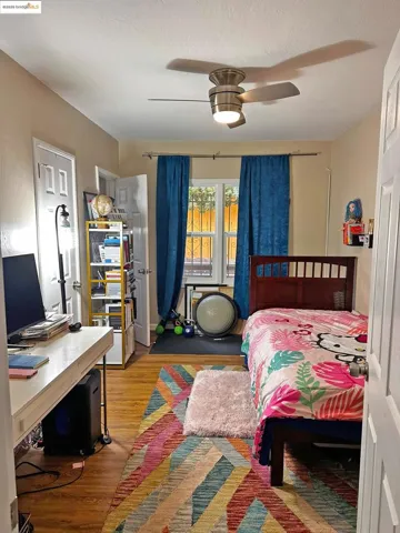 Bedroom featuring light wood finished floors, an office area, and ceiling fan
