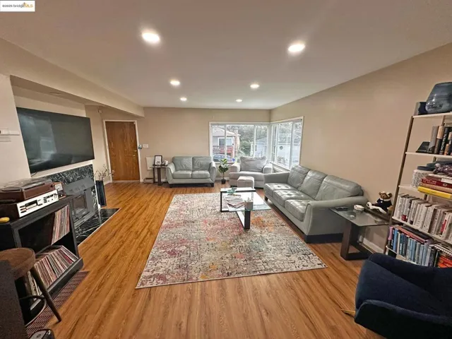 Living area with light wood-style floors, recessed lighting, and a tile fireplace