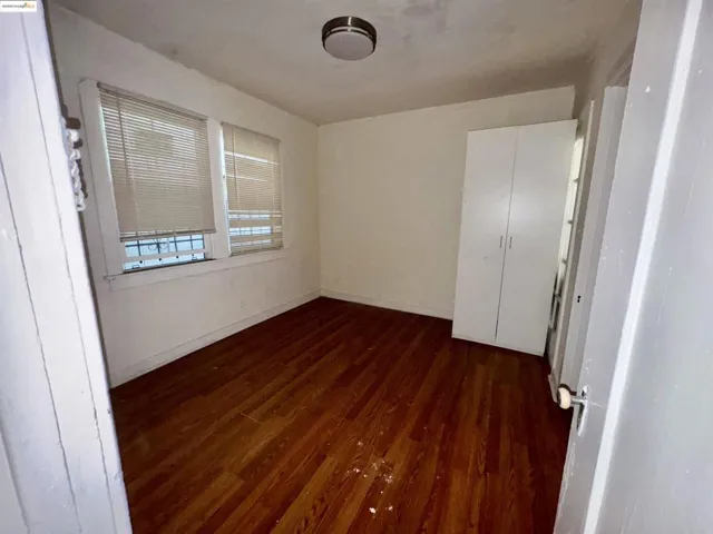 Unfurnished bedroom featuring dark wood finished floors and baseboards