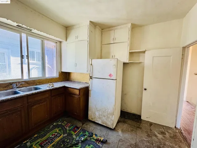 Kitchen featuring freestanding refrigerator, open shelves, and light countertops