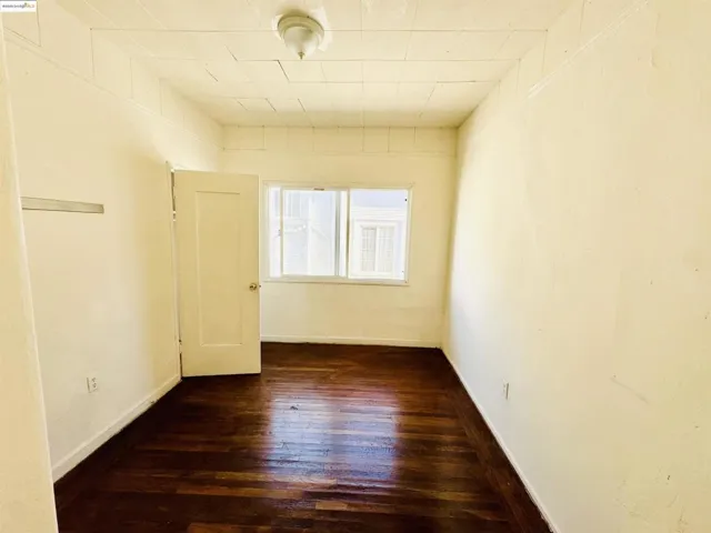Spare room with dark wood-type flooring and baseboards