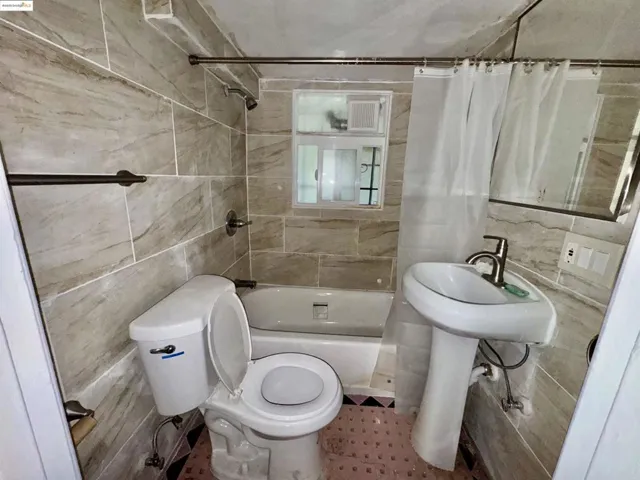 Full bath with tile walls and shower / tub combo with curtain