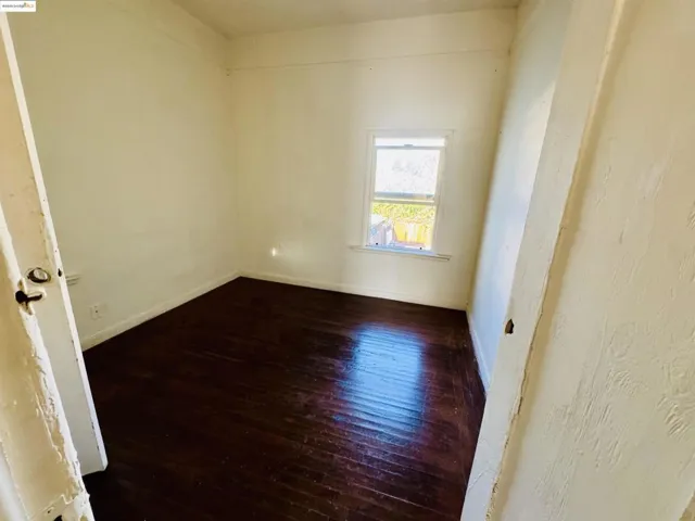 Unfurnished room featuring dark wood-style floors and baseboards