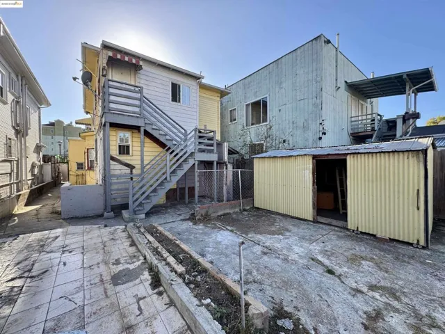 Back of property featuring stairs, a patio area, and a storage shed