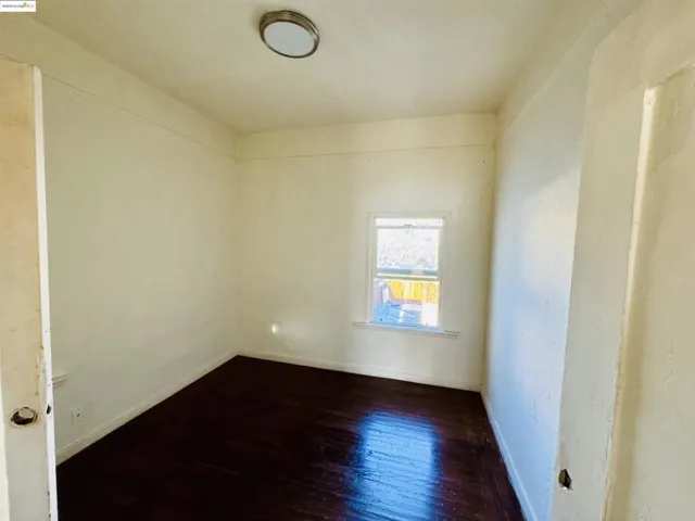Unfurnished room featuring dark wood finished floors and baseboards