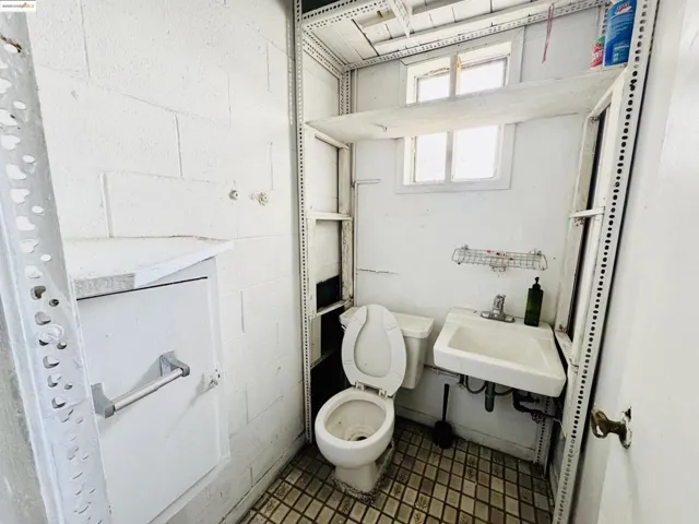 Half bathroom featuring concrete block wall and toilet